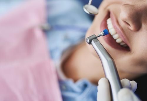 patient smiling with dental tool | dental exams southampton ny