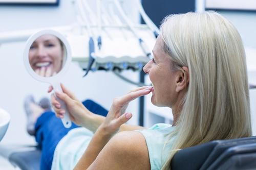 woman smiling into mirror | southampton dentist