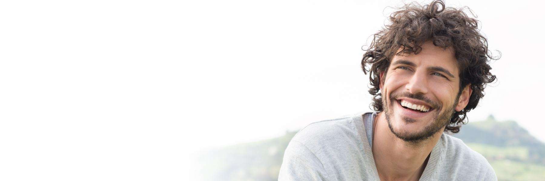 Man with curly hair glancing away and laughing while showing his teeth in New York