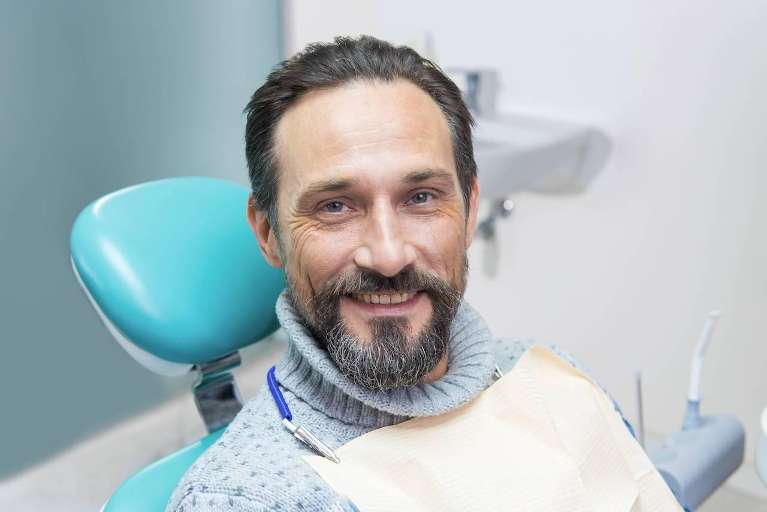 man sitting in dentist exam chair | cosmetic dentist southampton ny